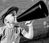 A young boy holding a vintage megaphone up to his mouth.