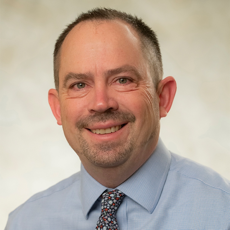 A smiling man wearing a blue shirt and a tie